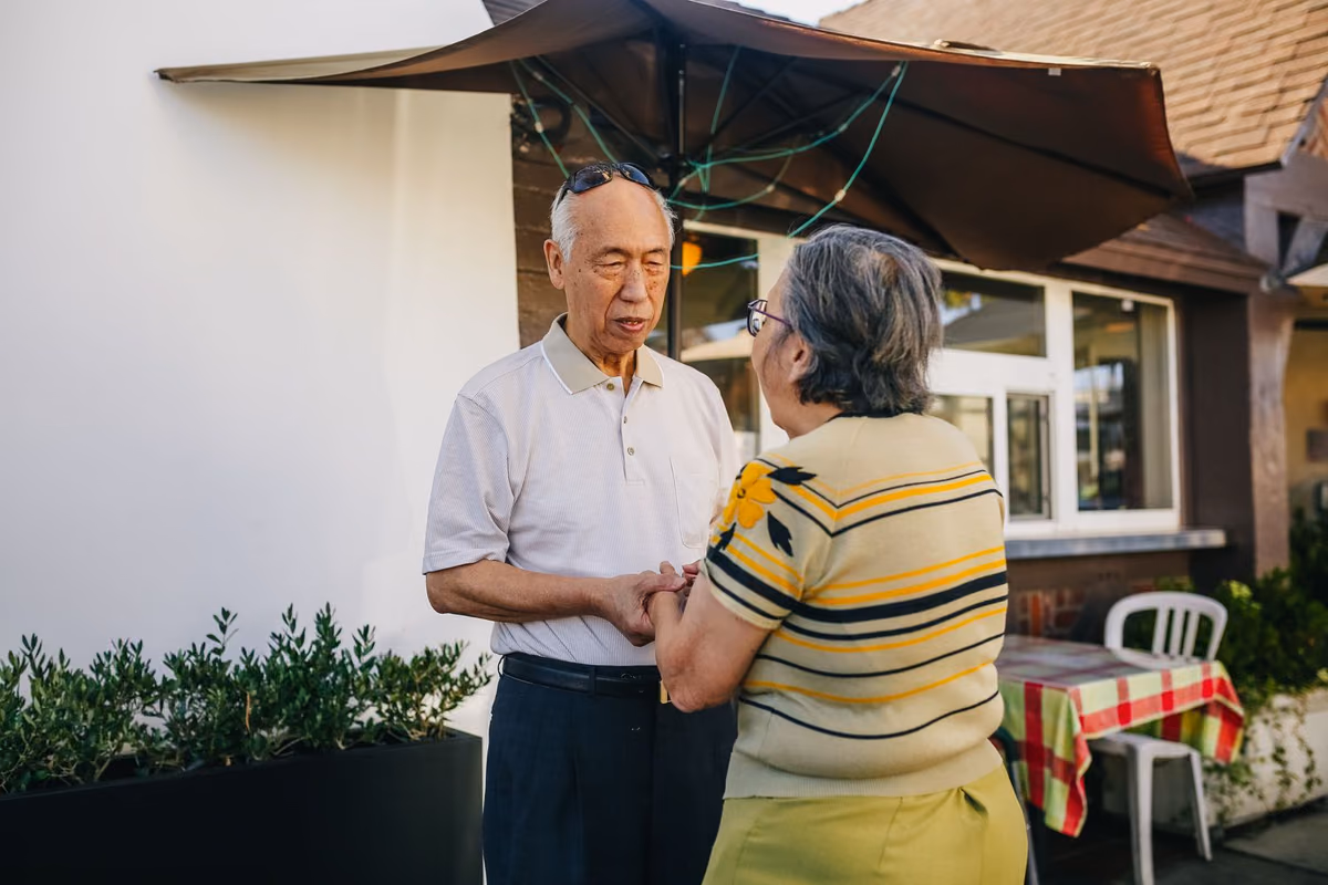 An older couple standing together outside their home, the kind of joint decision a full-arch implant treatment usually involves.