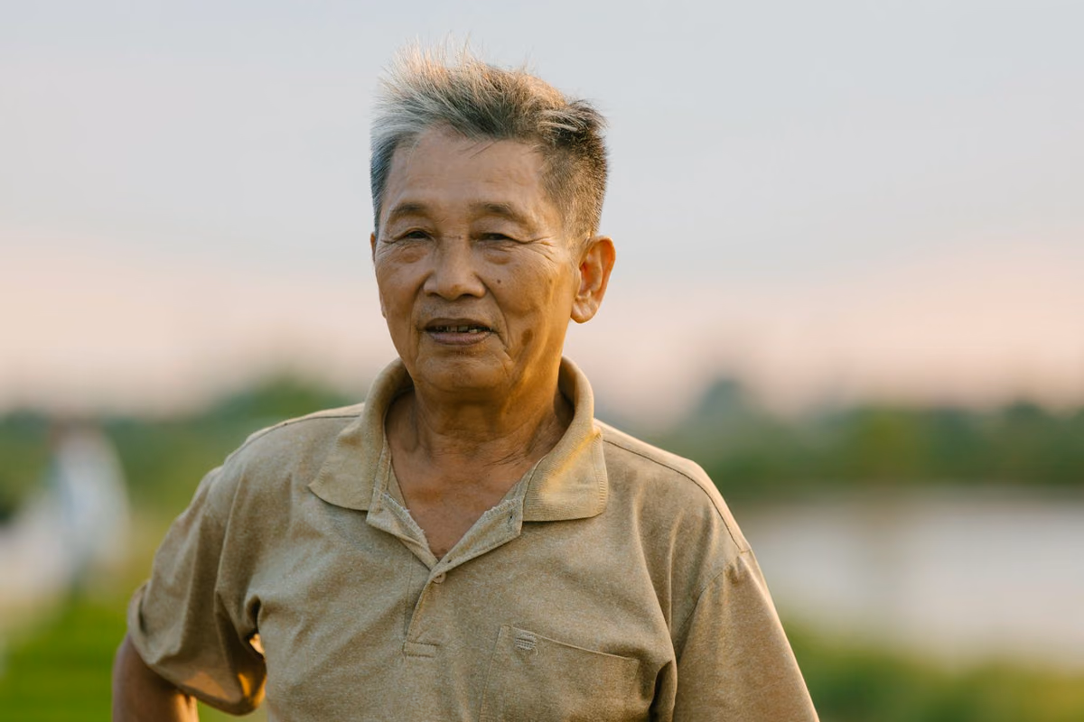 An older man outdoors at sunset, representing patients weighing the cost and timeline of bone grafting before dental implant treatment in Malaysia.