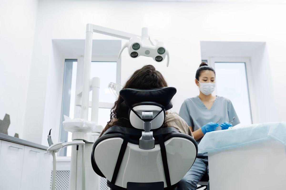 A dentist examining a patient in a modern Kuala Lumpur clinic, the assessment that determines which type of invisible braces suits each case.